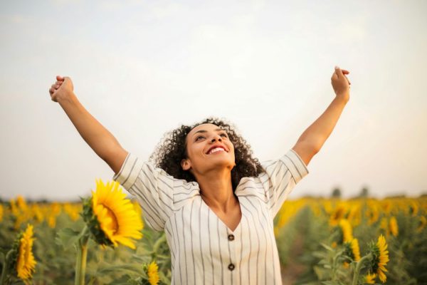 une femme heureuse qui s'étire dans un champs de tournesols