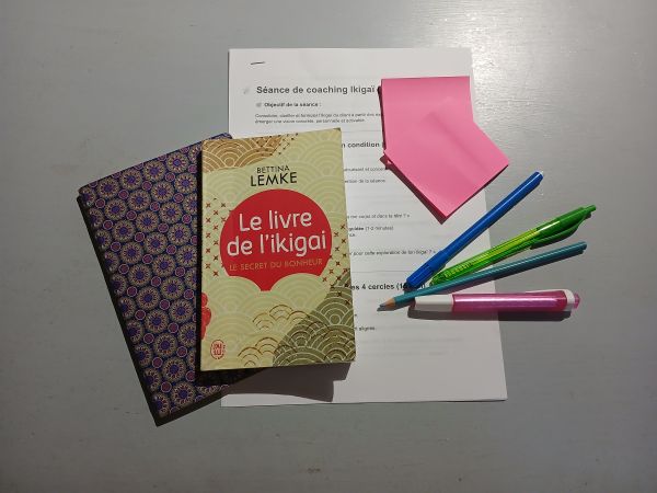un livre ikigai posé sur une feuille de route, avec des crayons et des posts it