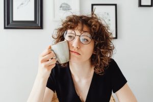 une femme qui tient une tasse contre sa joue
